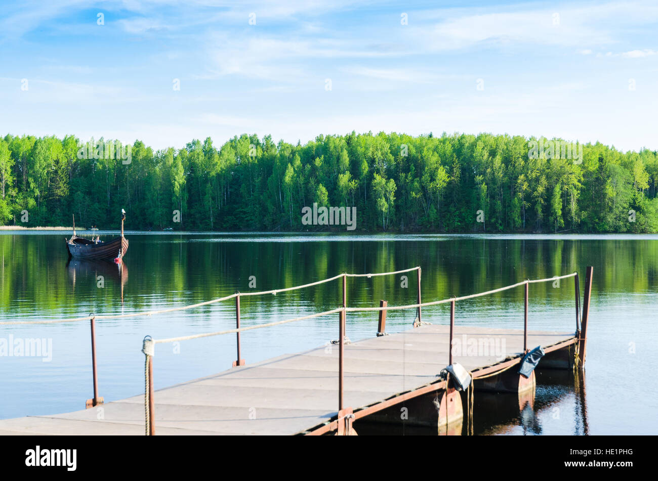 A fishing boat and jetty on a gorgeous forest lake Stock Photo