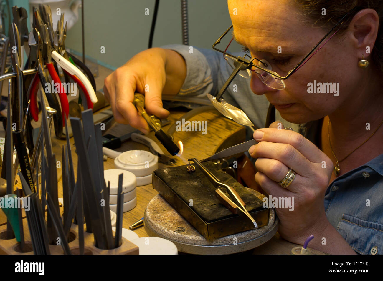 The Goldsmith working with an earring, solder a new pin Stock Photo