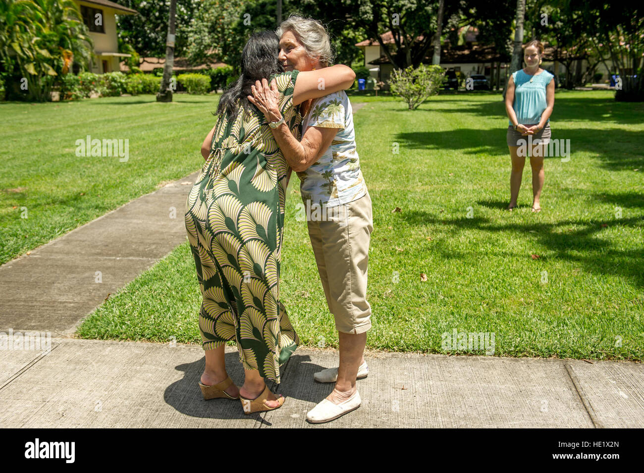 Shirley Waldron Nied, foreground right, hugs 15th Wing volunteer historian Jessie Higa, at Hickam Field at Joint Base Pearl Harbor Hickam on Aug 8, 2016, outside the home where, a then five-year-old, Neid lived in during the Japanese attack on Hickam Field and Pearl Harbor on Dec 7, 1941.  J.M. Eddins Jr. Stock Photo