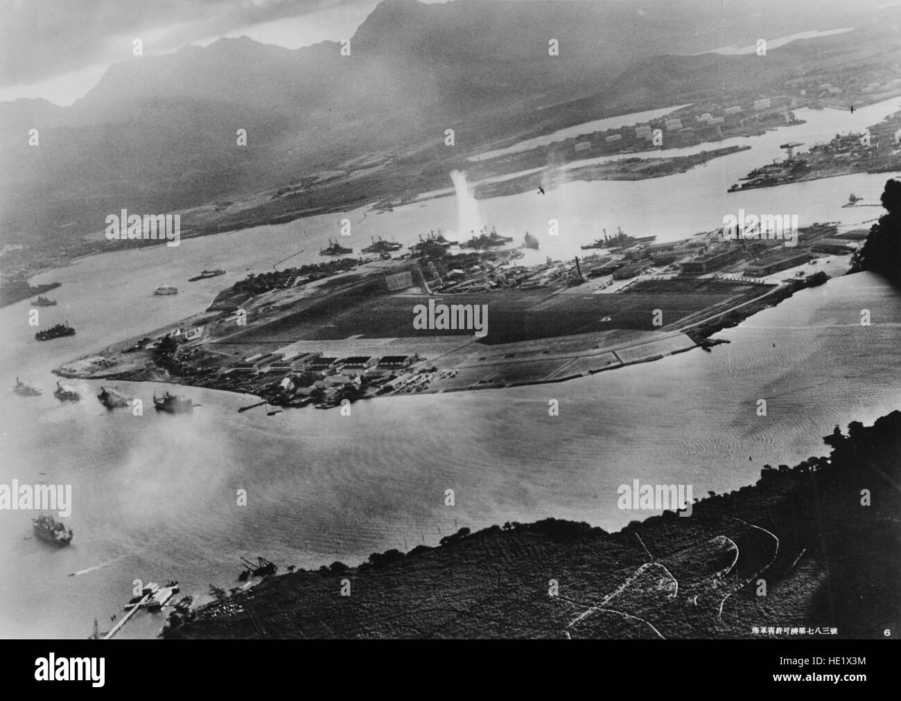 Photograph taken from a Japanese plane during the torpedo attack on ships moored on both sides of Ford Island. View looks about east, with the supply depot, submarine base and fuel tank farm in the right center distance. A torpedo has just hit USS West Virginia on the far side of Ford Island center. Other battleships moored nearby are from left: Nevada, Arizona, Tennessee inboard of West Virginia, Oklahoma torpedoed and listing alongside Maryland, and California. On the near side of Ford Island, to the left, are light cruisers Detroit and Raleigh, target and training ship Utah and seaplane ten Stock Photo