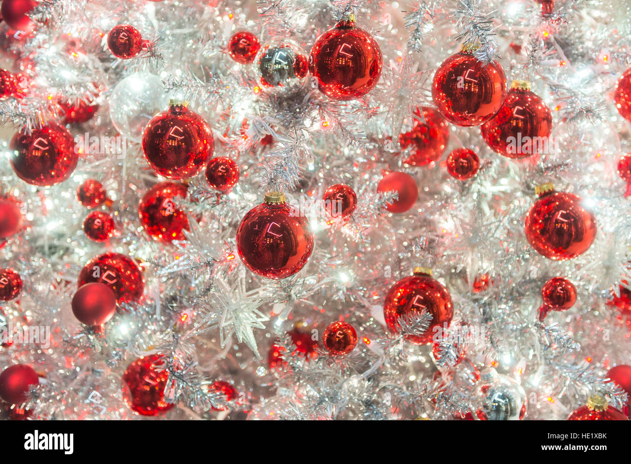Shiny red holiday ornaments decorate a modern shiny silver Christmas