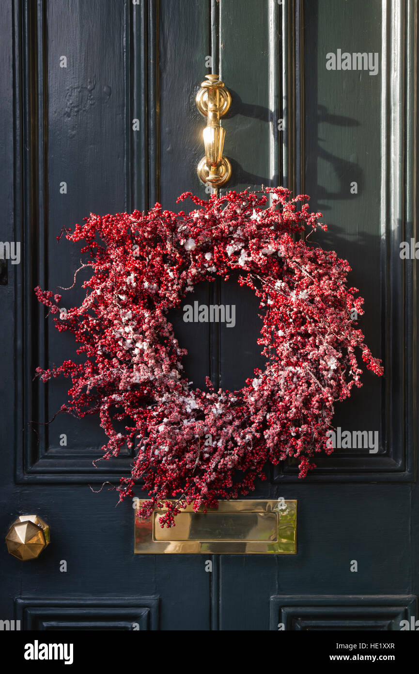 Christmas red berry wreath on wooden door. Cotswolds, Gloucestershire, England Stock Photo