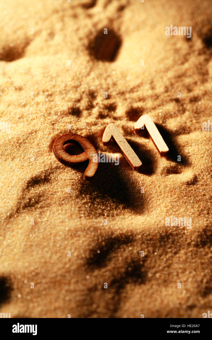 Emergency services concept. Wooden numbers 911 on sand background with shadow Stock Photo