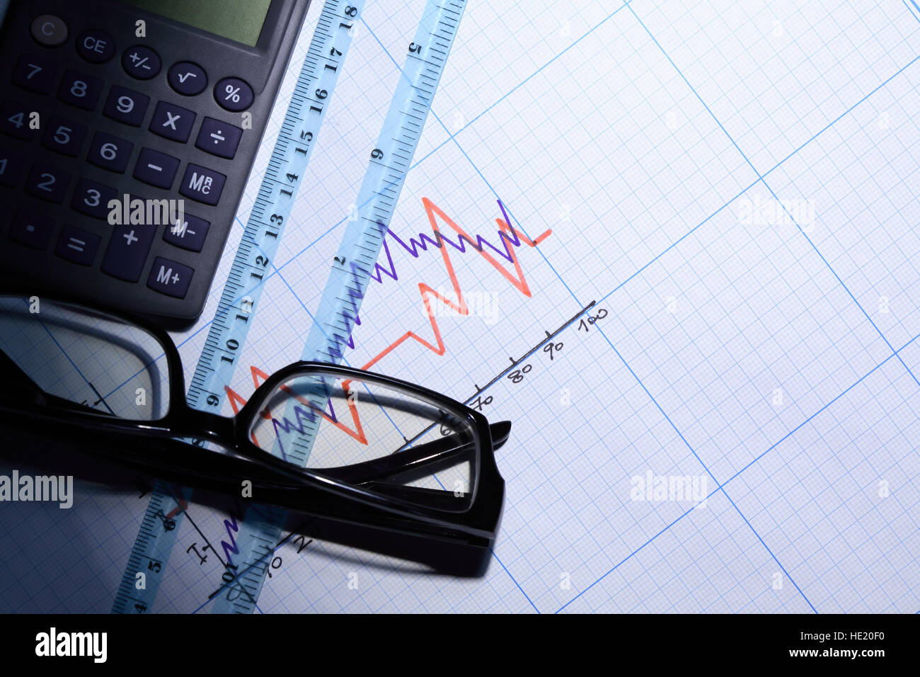 Calculator near ruler and spectacles on graph paper with diagram Stock Photo