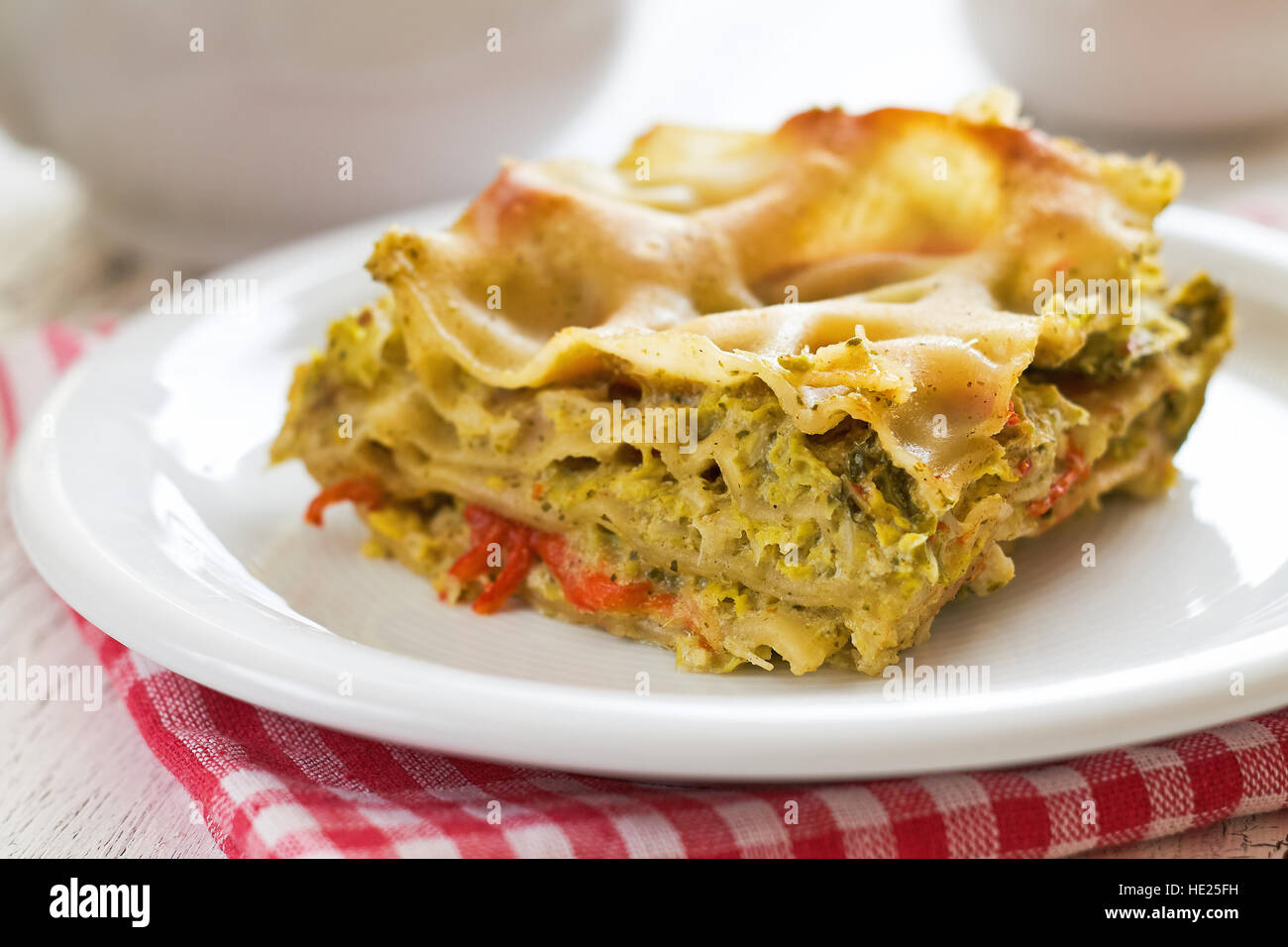 Vegan lasagna with savoy cabbage, tofu and red bell pepper served on white plate Stock Photo