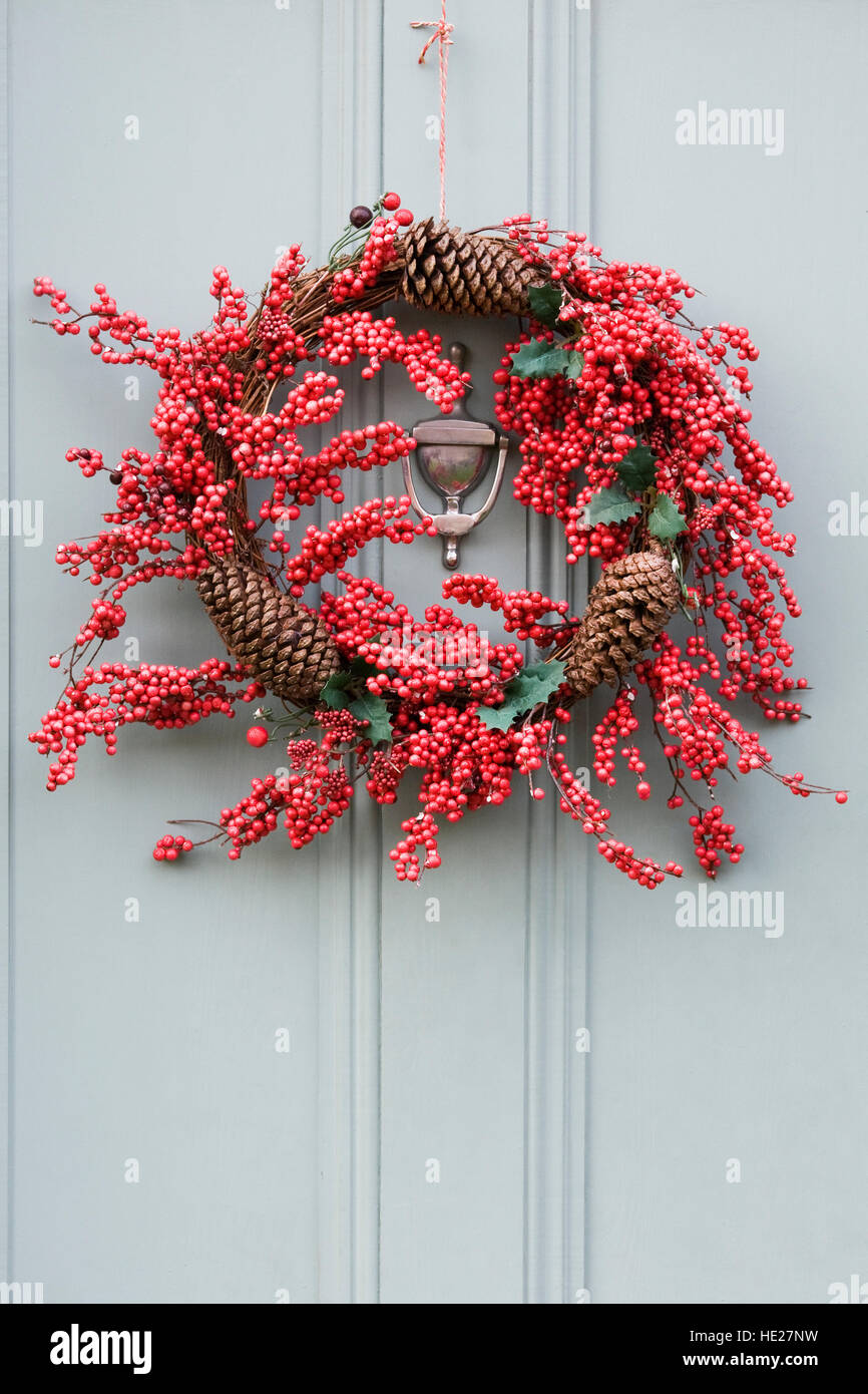 Decorative Christmas wreath hanging on a grey front door. Stock Photo