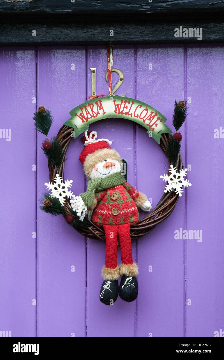 Decorative Christmas wreath hanging on a purple front door. Stock Photo