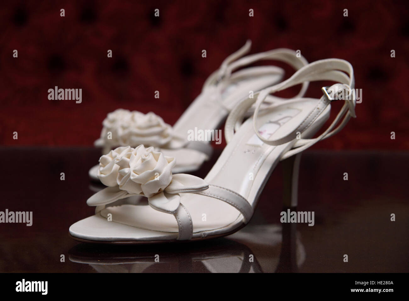 Bride's wedding shoes, high heels, white, with fabric roses on the toe straps Stock Photo