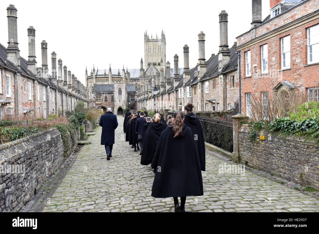 Choristers from Wells Cathedral Choir walking along Vicars Close with Wells Cathedral in the