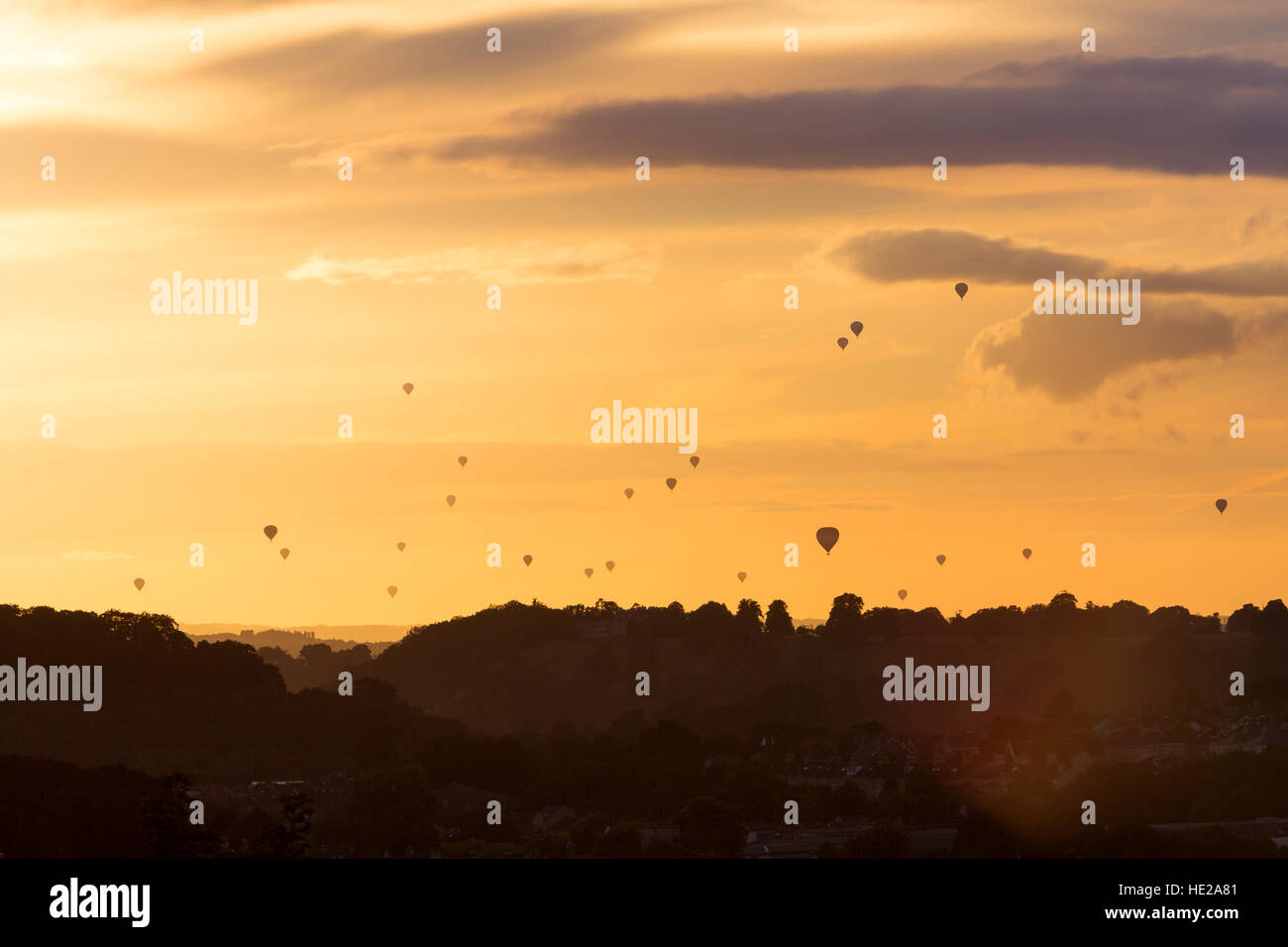 Silhouetted hot air balloons at sunset over the Avon Valley near Bath during the mass ascent, part of the Bristol Balloon Fiesta on 13th August 2016. Stock Photo