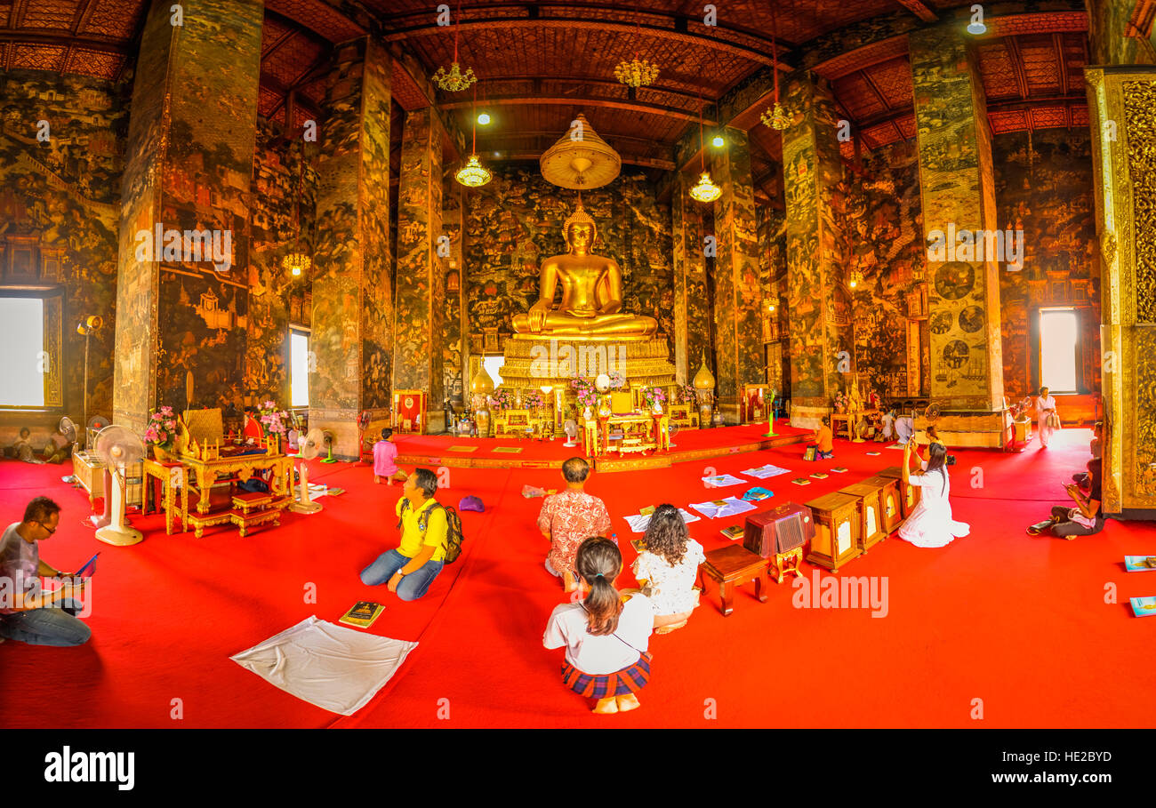 Photo of people kneeling on ground in front of big statue of Buddha in temple Suthat Wat in Bangkok, Thailand. Stock Photo
