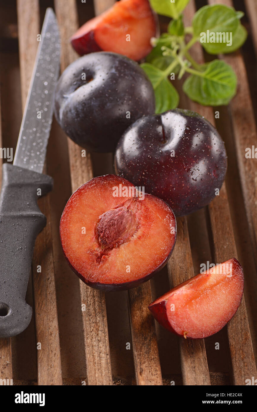 plums cut on wooden chopping board Stock Photo