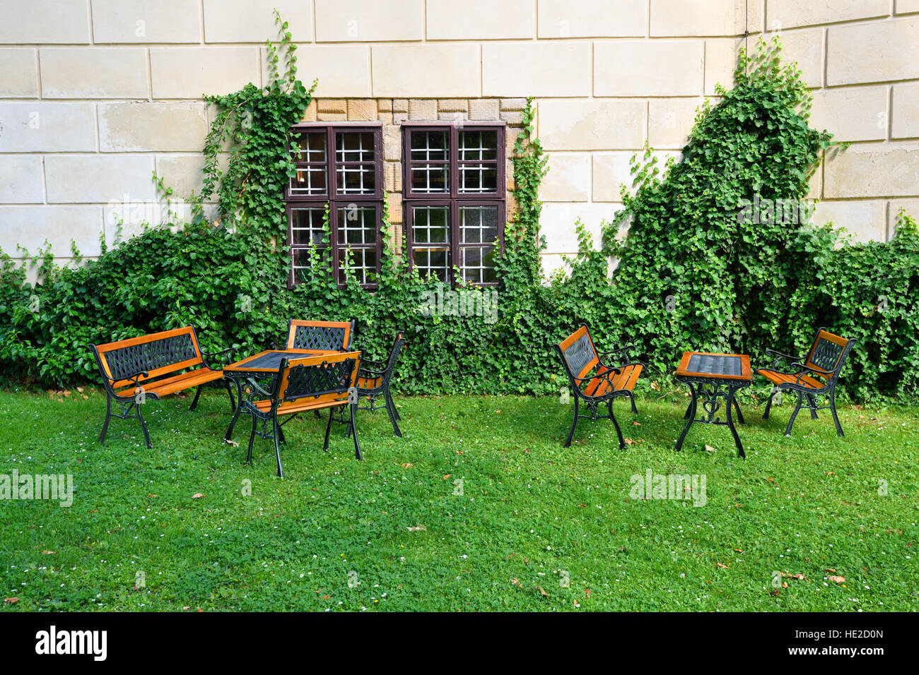 Garden with garden furniture in front of a wall overgrown by green ivy Stock Photo