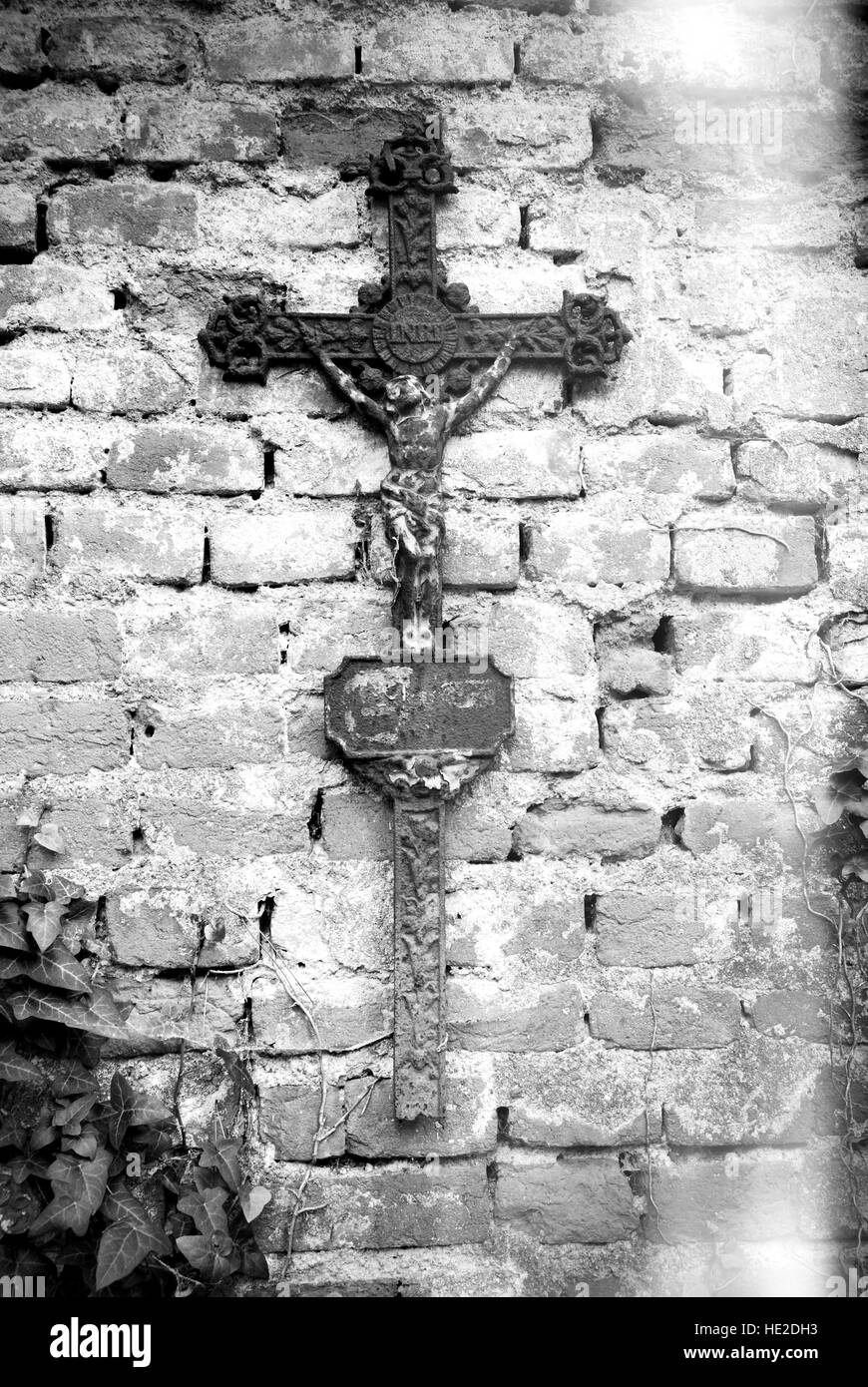 Rusty christian cross with Jesus Christ statue hanging on an old brick wall Stock Photo