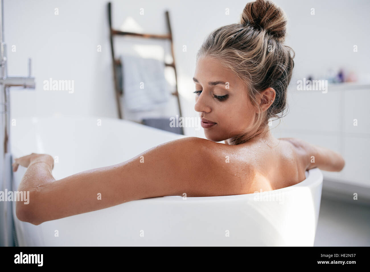 Close up shot of young woman in bathtub. Female taking bath in bathroom. Stock Photo
