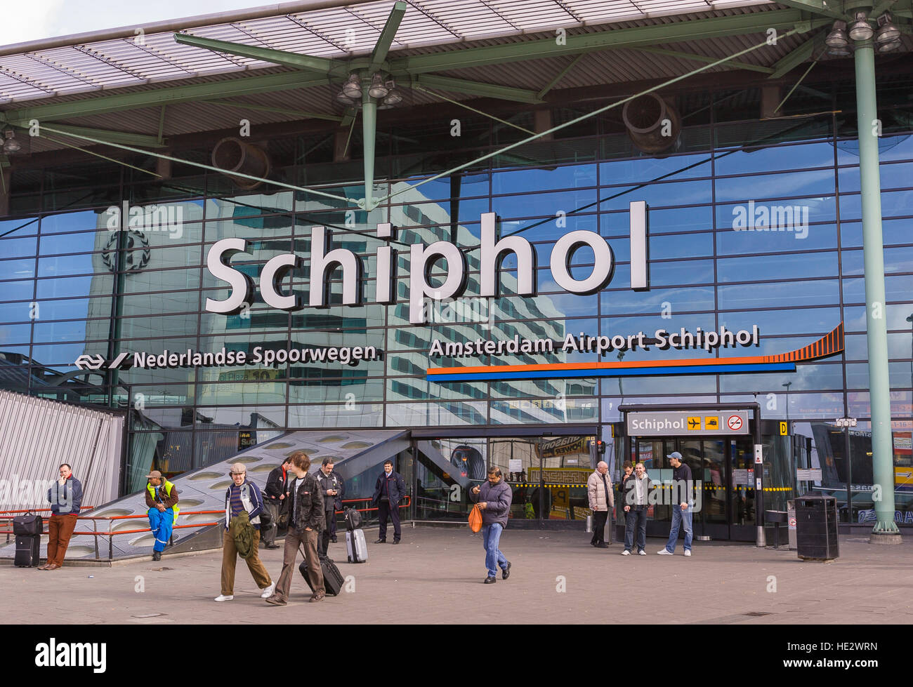 AMSTERDAM, NETHERLANDS - People in front of Schiphol International Airport terminal building with sign. Stock Photo