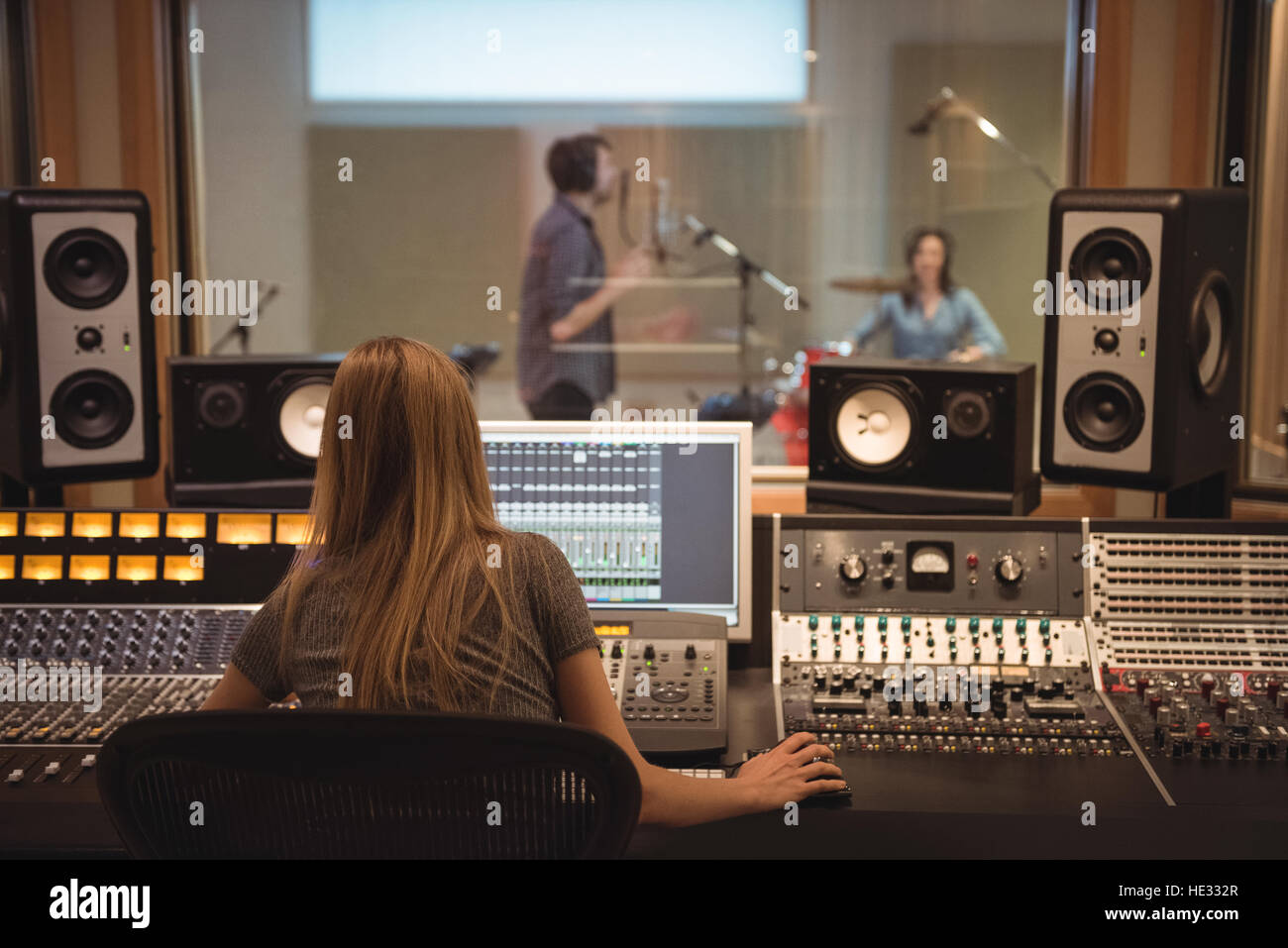 Rear view of audio engineer using sound mixer in recording studio Stock