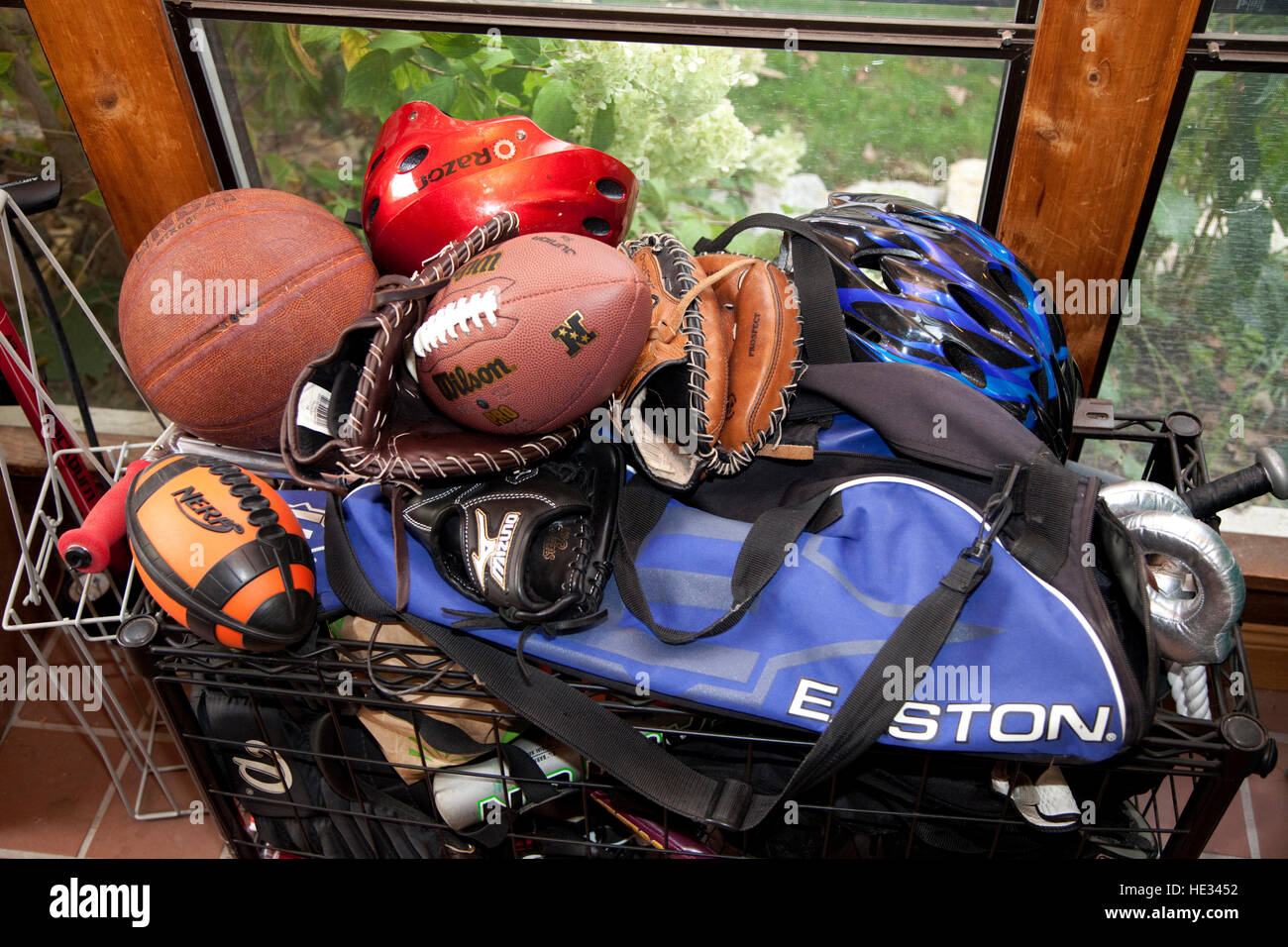 Basket full of kids & teens sports equipment basketball football helmets baseball mitts bat. St Paul Minnesota MN USA Stock Photo
