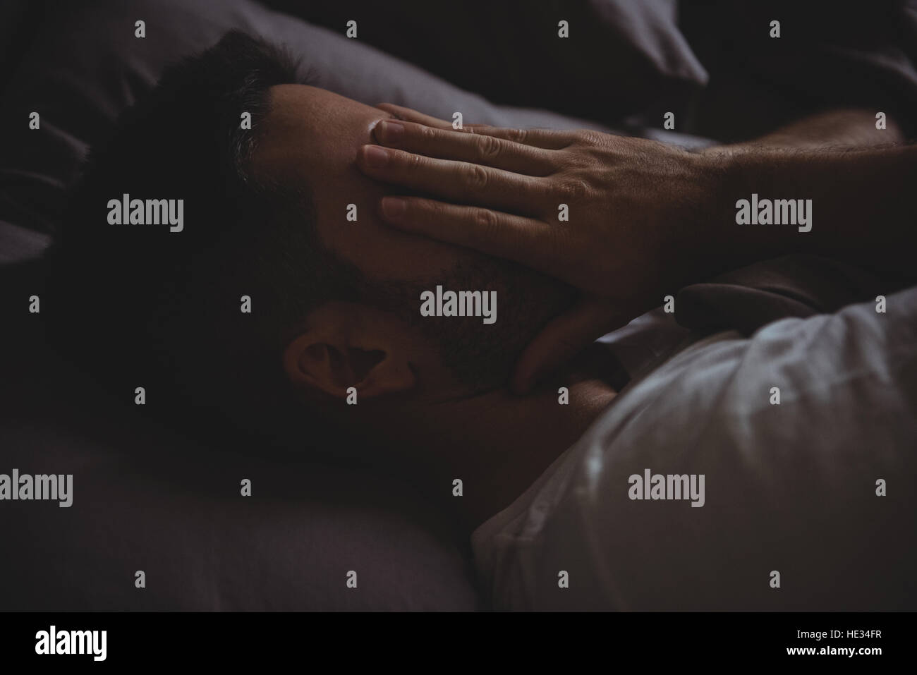 Closeup of man rubbing his eyes while sleeping in his bed at home