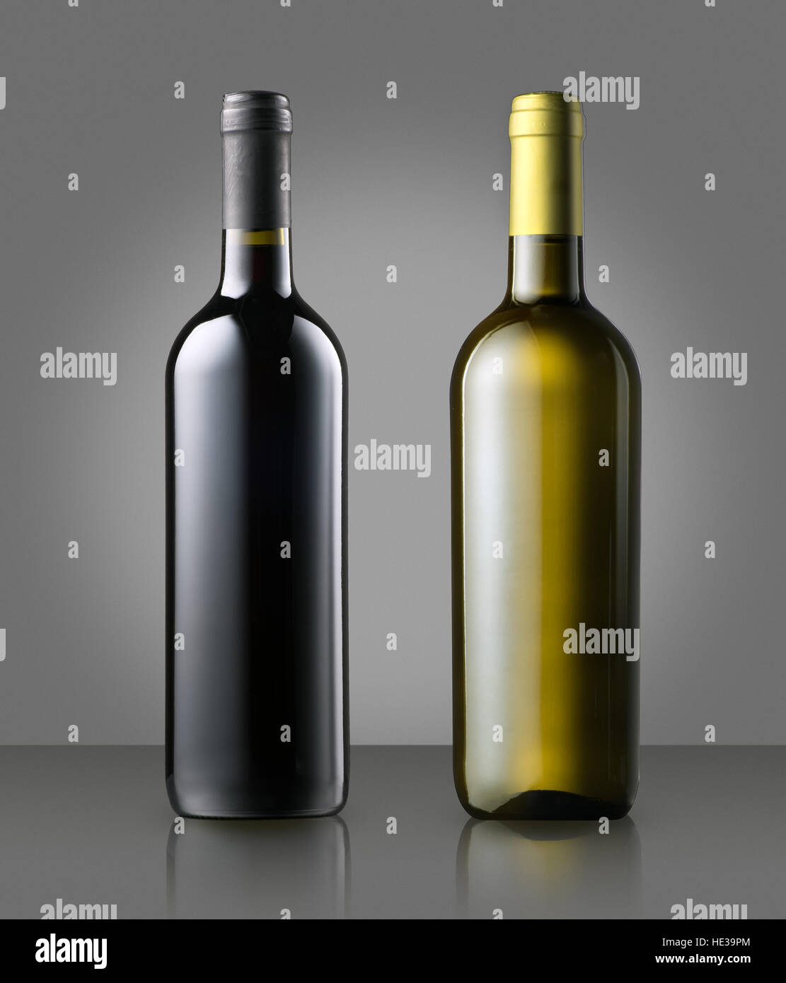 Unlabeled corked full red and white wine bottles standing side by side on gray conceptual of a winery, wine making, viticulture Stock Photo