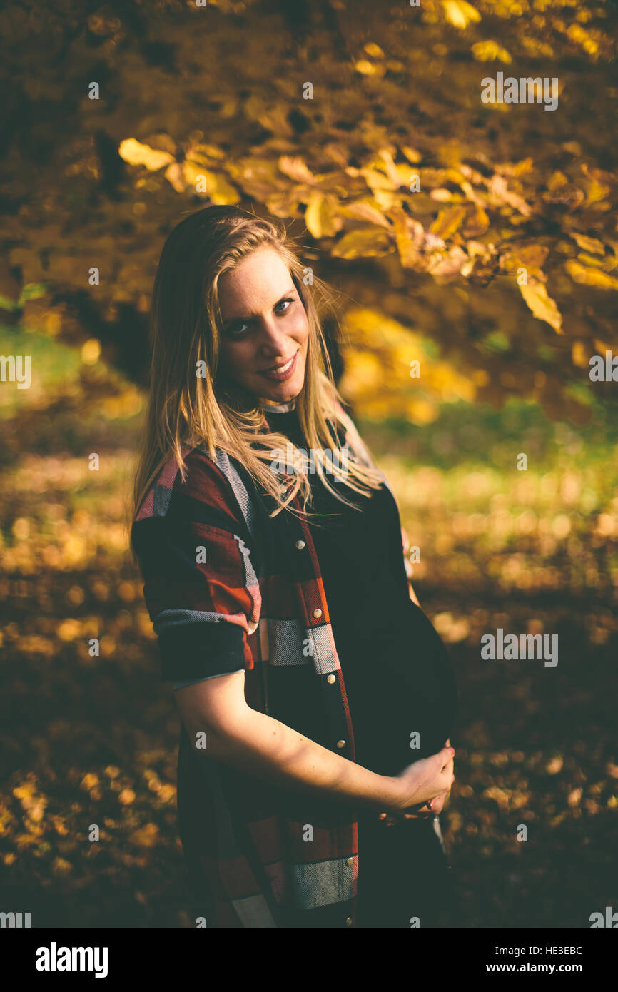 Young pregnant woman posing in autumn park Stock Photo - Alamy