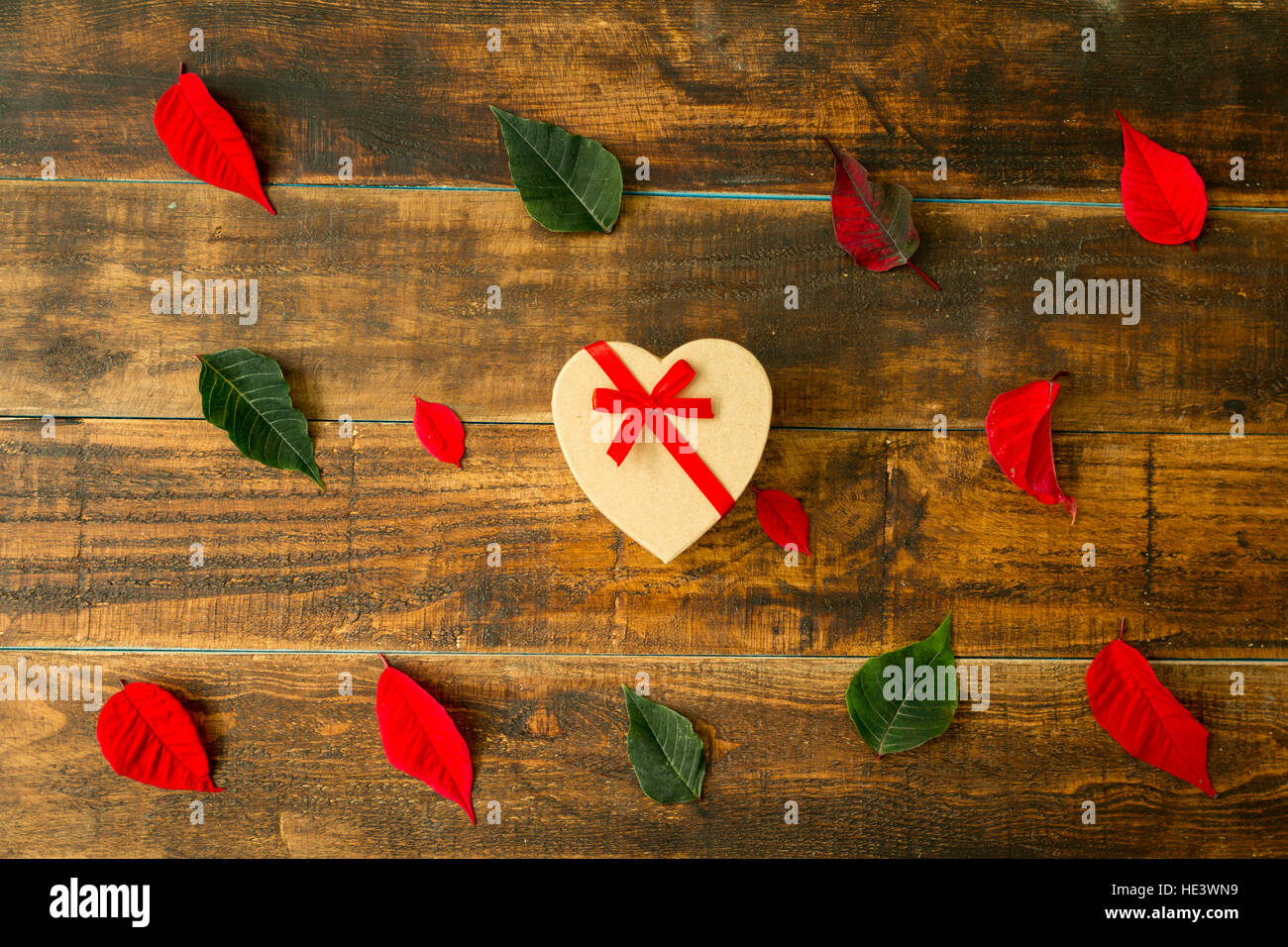 Present with heart shape green and red leaves on a wooden background ...