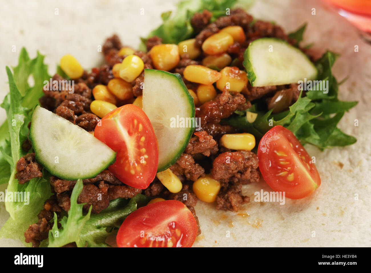 preparing homemade open tortilla with beef, frisee and corn Stock Photo