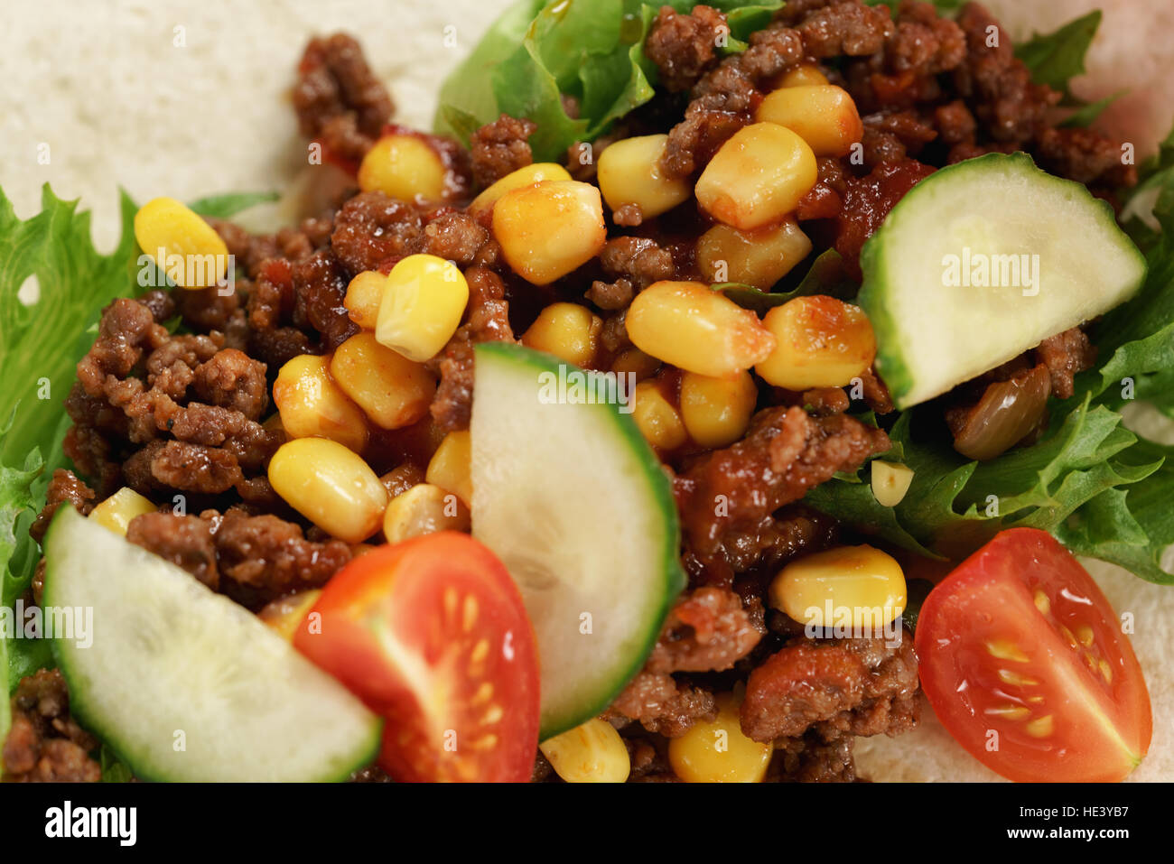 preparing homemade open tortilla with beef, frisee and corn Stock Photo