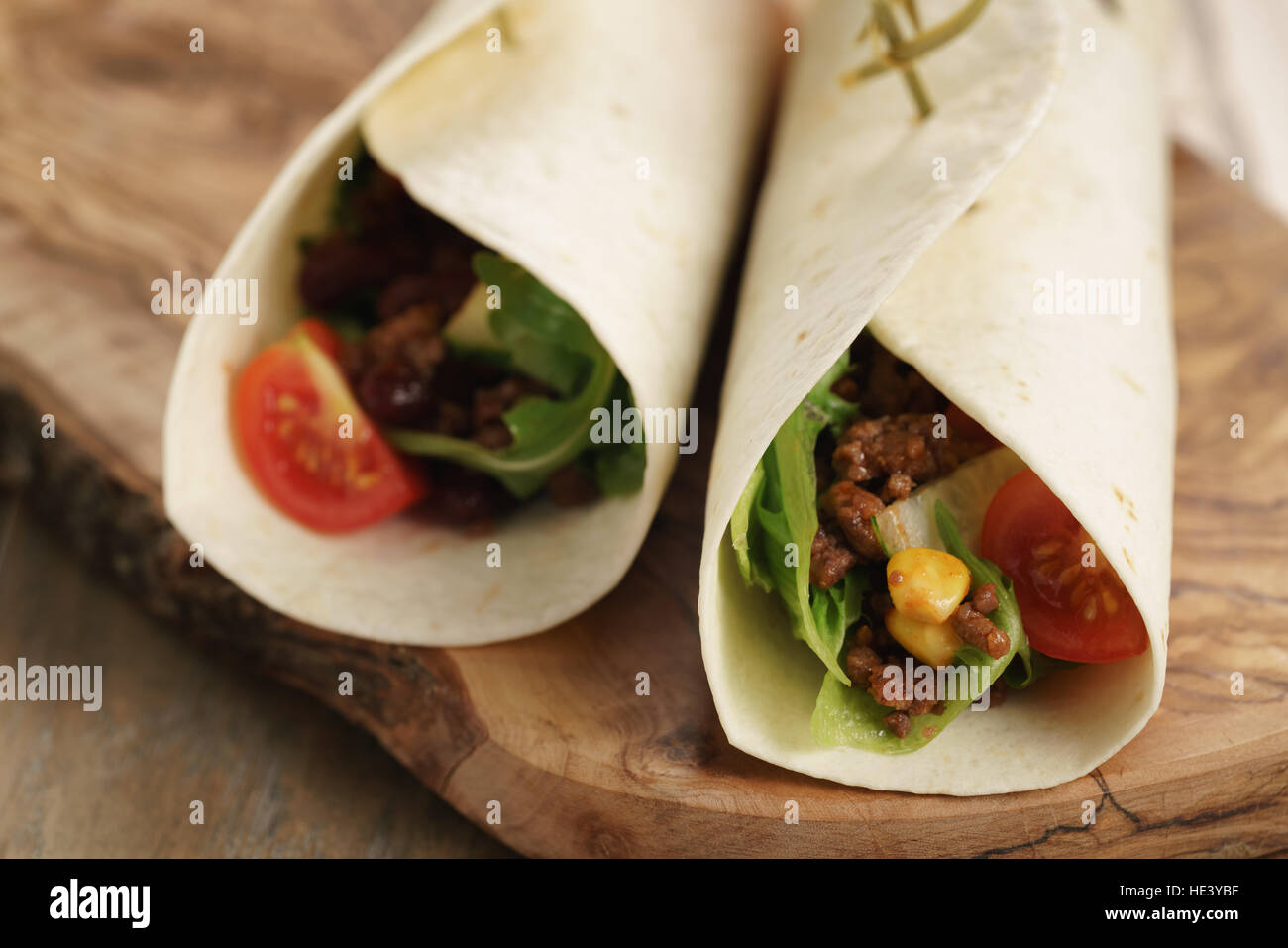 fresh homemade tortilla wrap sandwiches with beef and vegetables on olive board Stock Photo