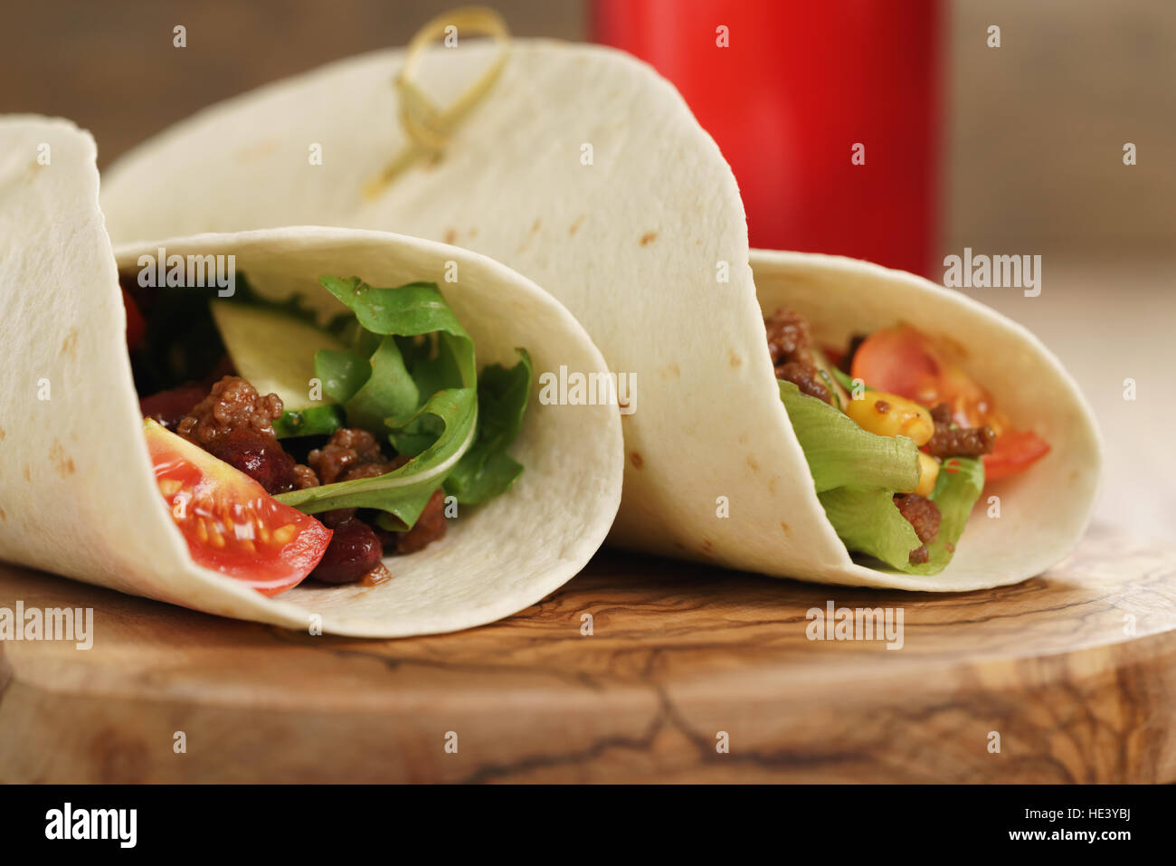 fresh homemade tortilla wrap sandwiches with beef and vegetables on olive board Stock Photo