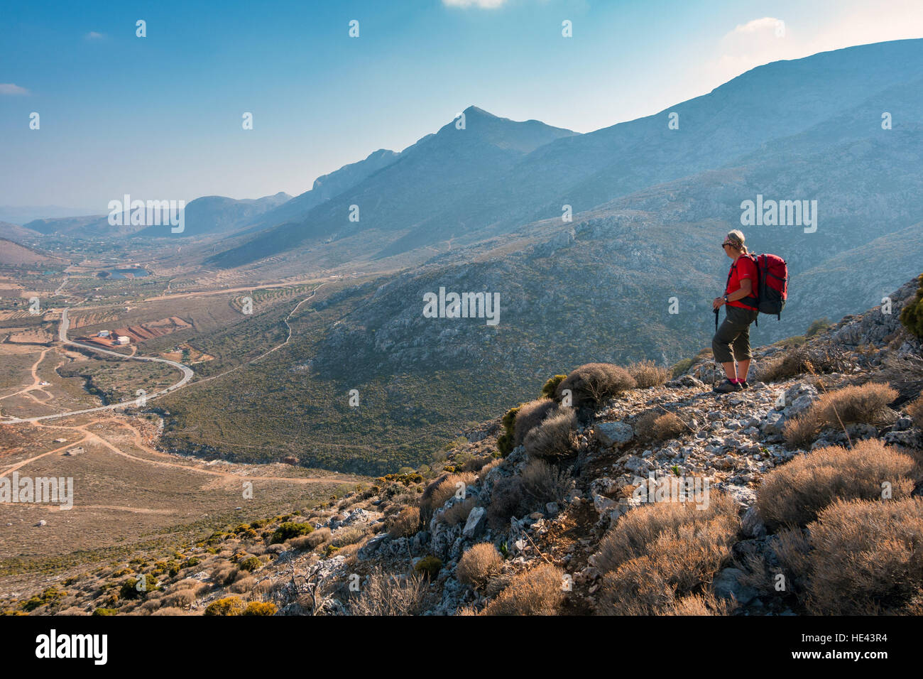 Female figure in red with rucksack  in mountains of Kalymnos, Greece Stock Photo