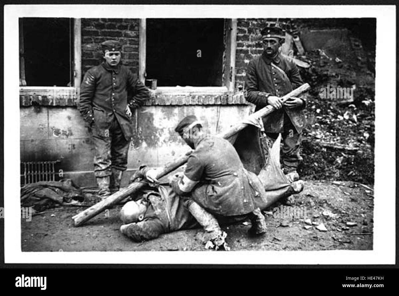 This historical image shows German prisoners of war during World War II tending to one of their wounded comrades. The scene captures a moment of compassion amidst the chaos of war, emphasizing the human element in a time of conflict. The black-and-white photo offers a somber look at the reality of wartime conditions and prisoner life. Stock Photo
