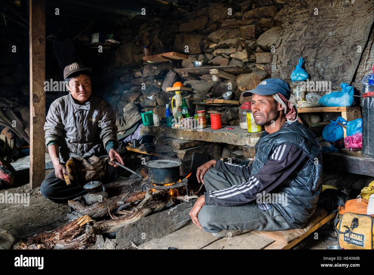 Two yak herders are preparing food in their simple hut at Ice Lake Stock Photo