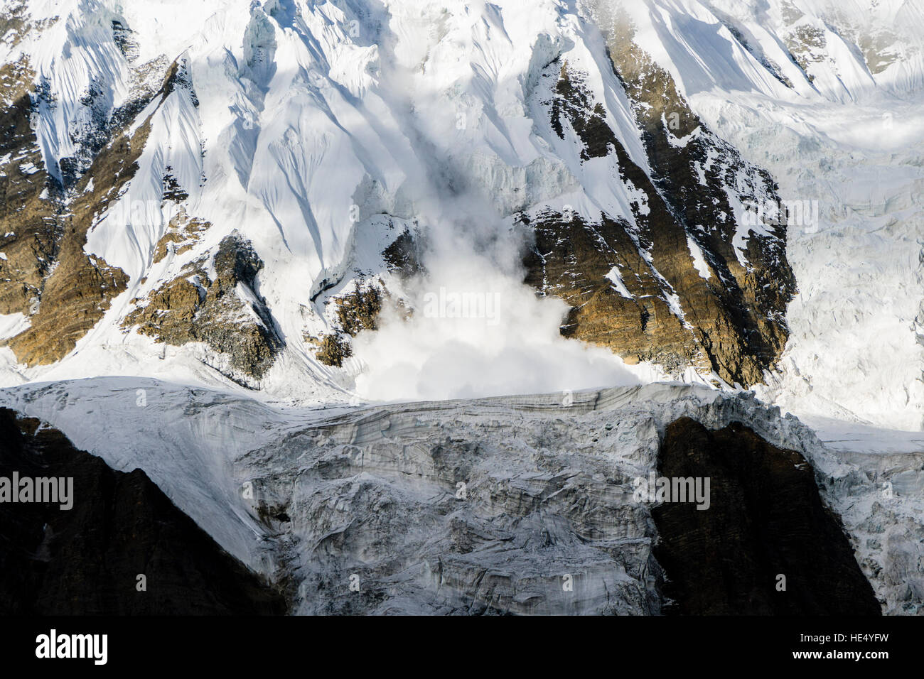 An ice avalanche is shooting down an icy rock slope just above Tilicho Lake Stock Photo