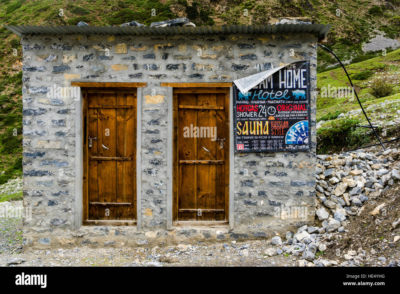 A small hut with 2 doors outside of Muktinath with a Russian Sauna advertisement Stock Photo