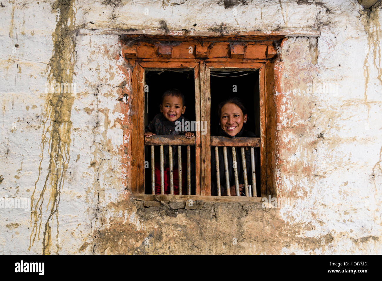 A young woman and her son child are looking out of the window of a farmhouse Stock Photo