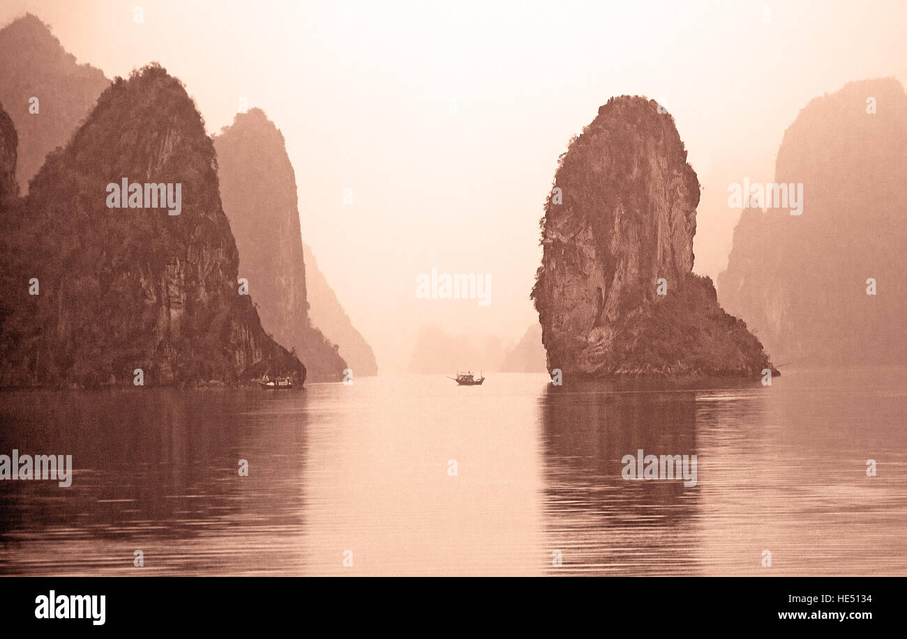 King Kong rock and a fishing boat for the scale at sunrise. Ha Long Bay, Vietnam. Film scan. Stock Photo