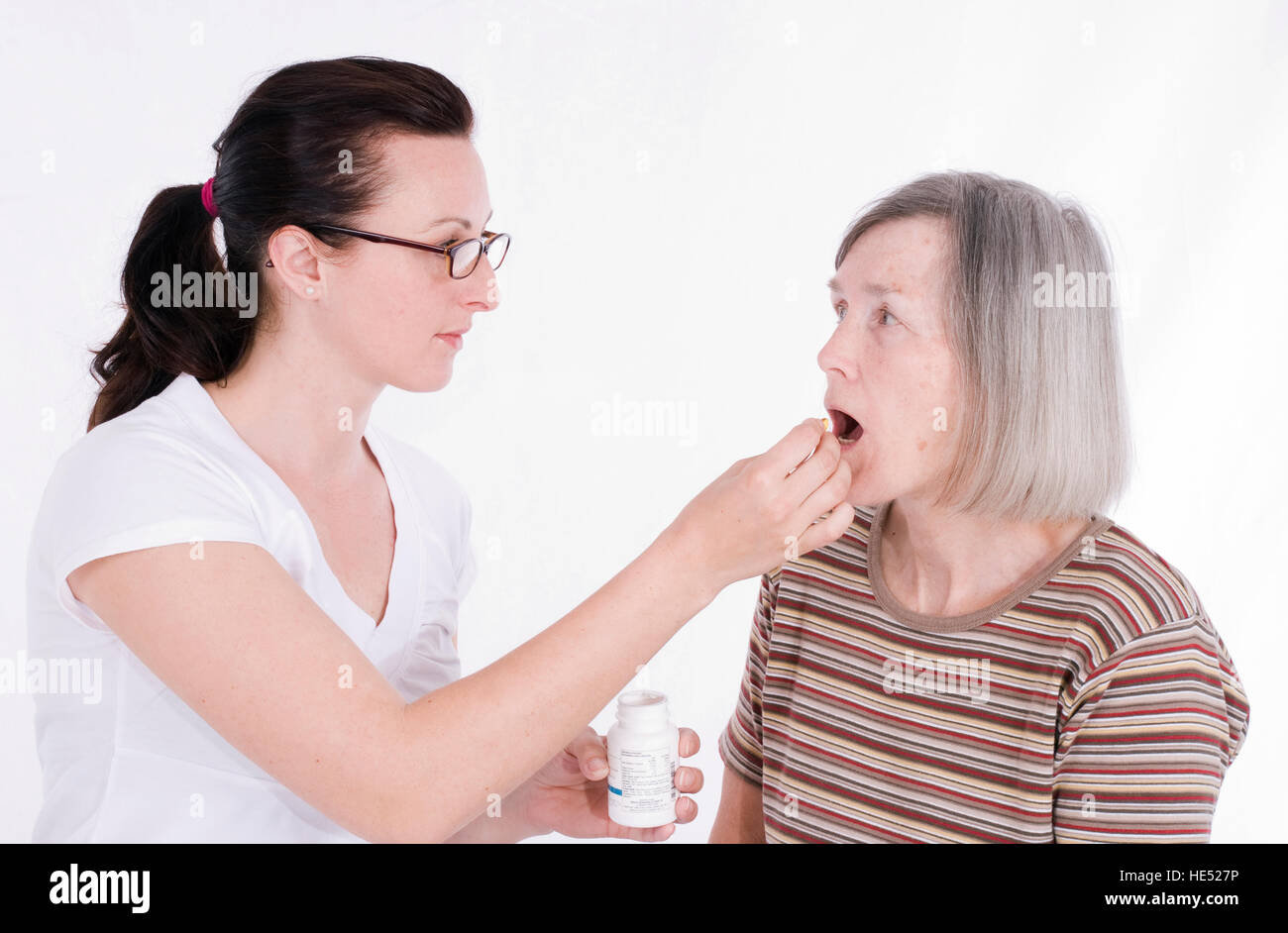 Elderly woman being administered pills from a nurse Stock Photo