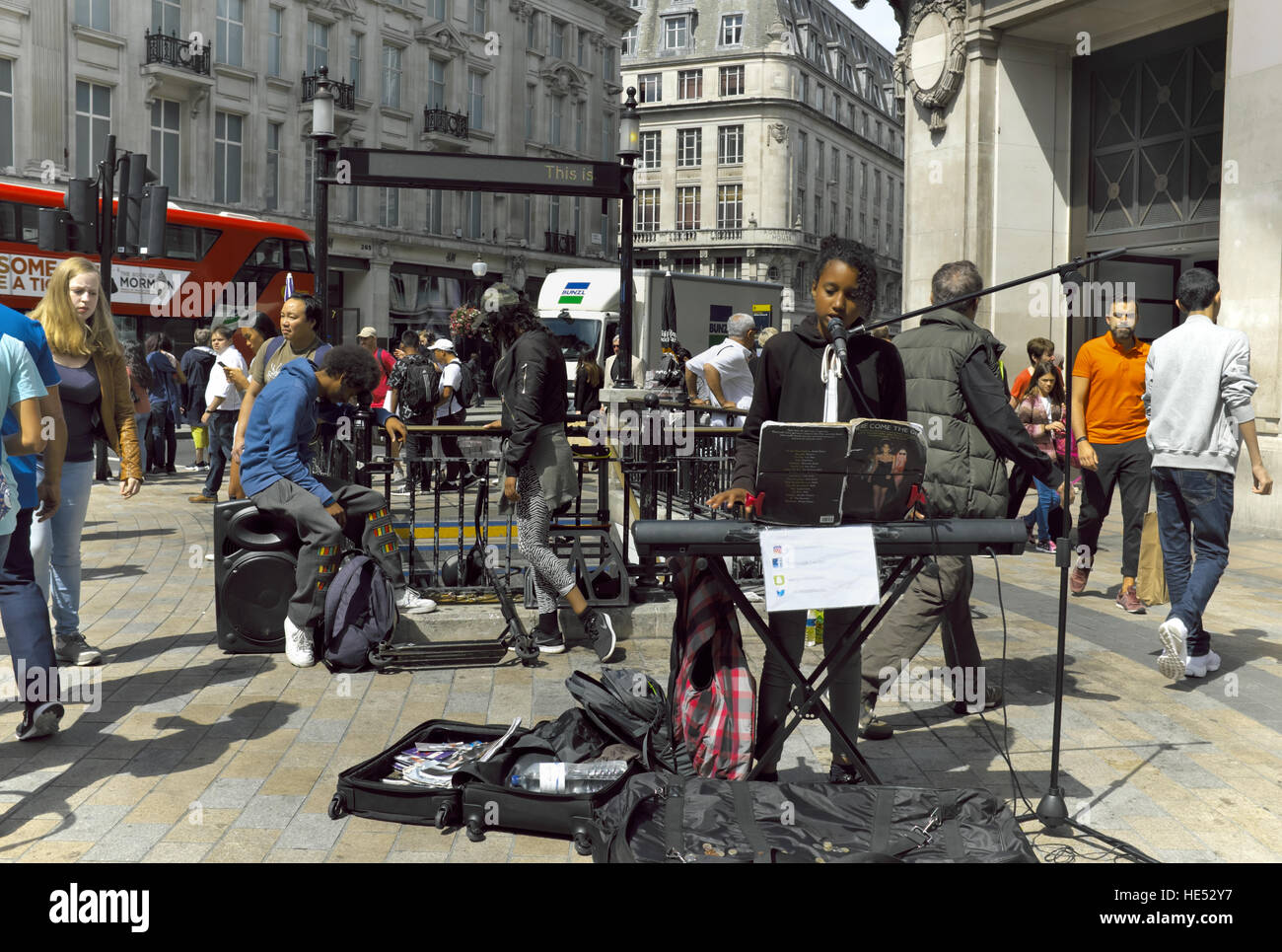 A solo woman busker on a busy street corner in London, England singing for tips. Stock Photo