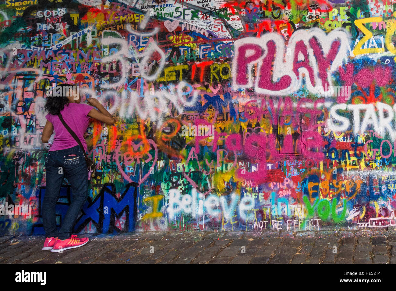 Girl adds message to John Lennon Wall in Prague Stock Photo