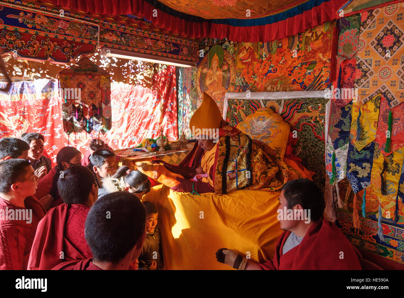 Lhasa: Monastery Sera; Pilgrims stand to receive the blessing of a lama, they get a push with a pillow on their heads, monks ensure a speedy process, Stock Photo