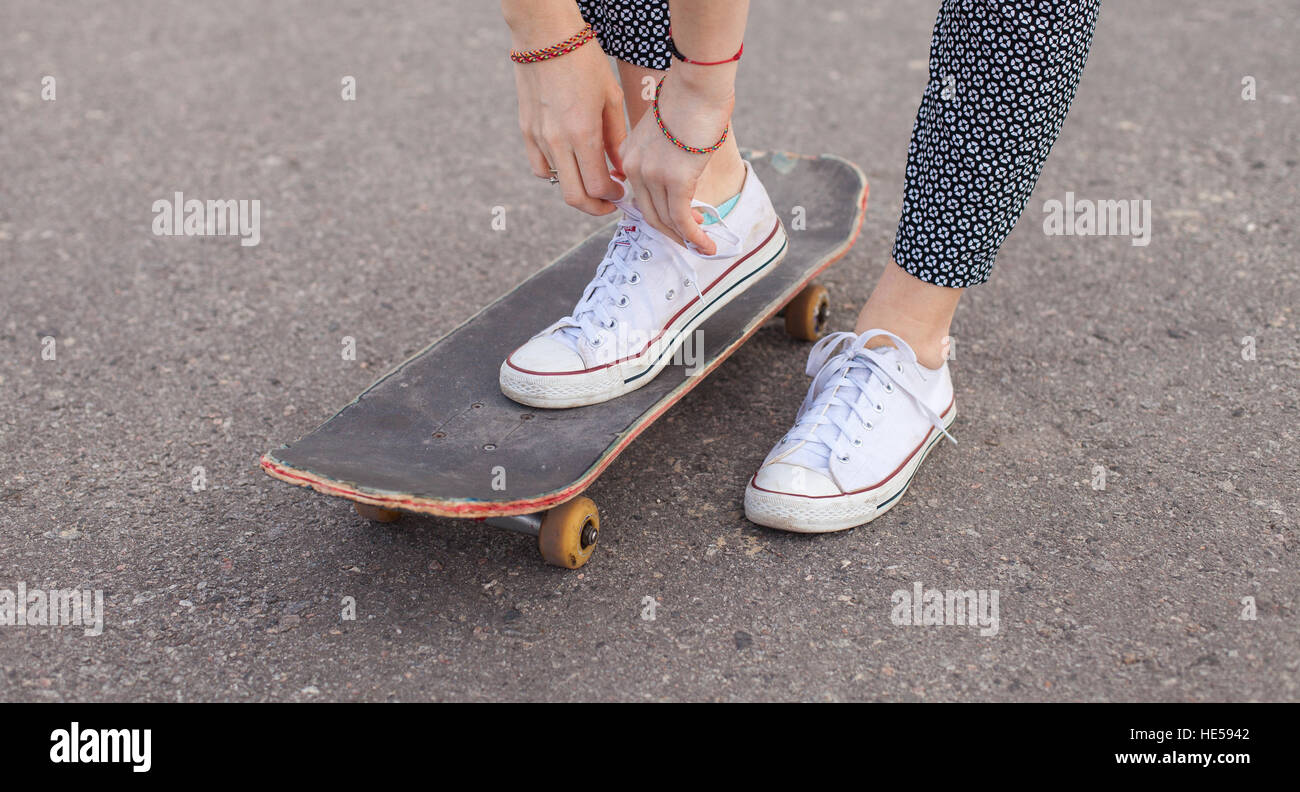 Woman on the skateboard tying shoelaces Stock Photo Alamy