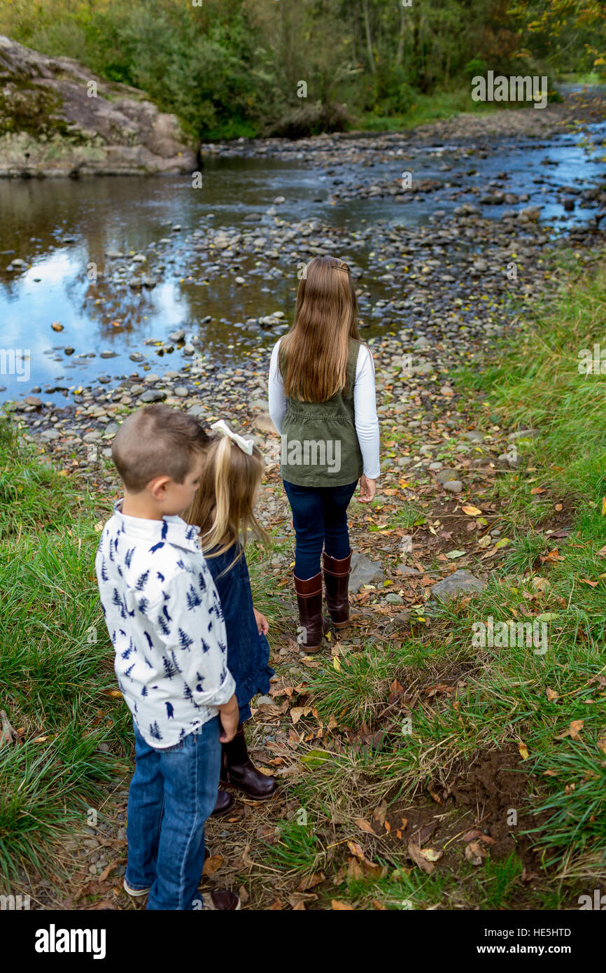 Three kids who are siblings in a candid lifestyle photo outdoors along the banks of the McKenzie River in Oregon. Stock Photo