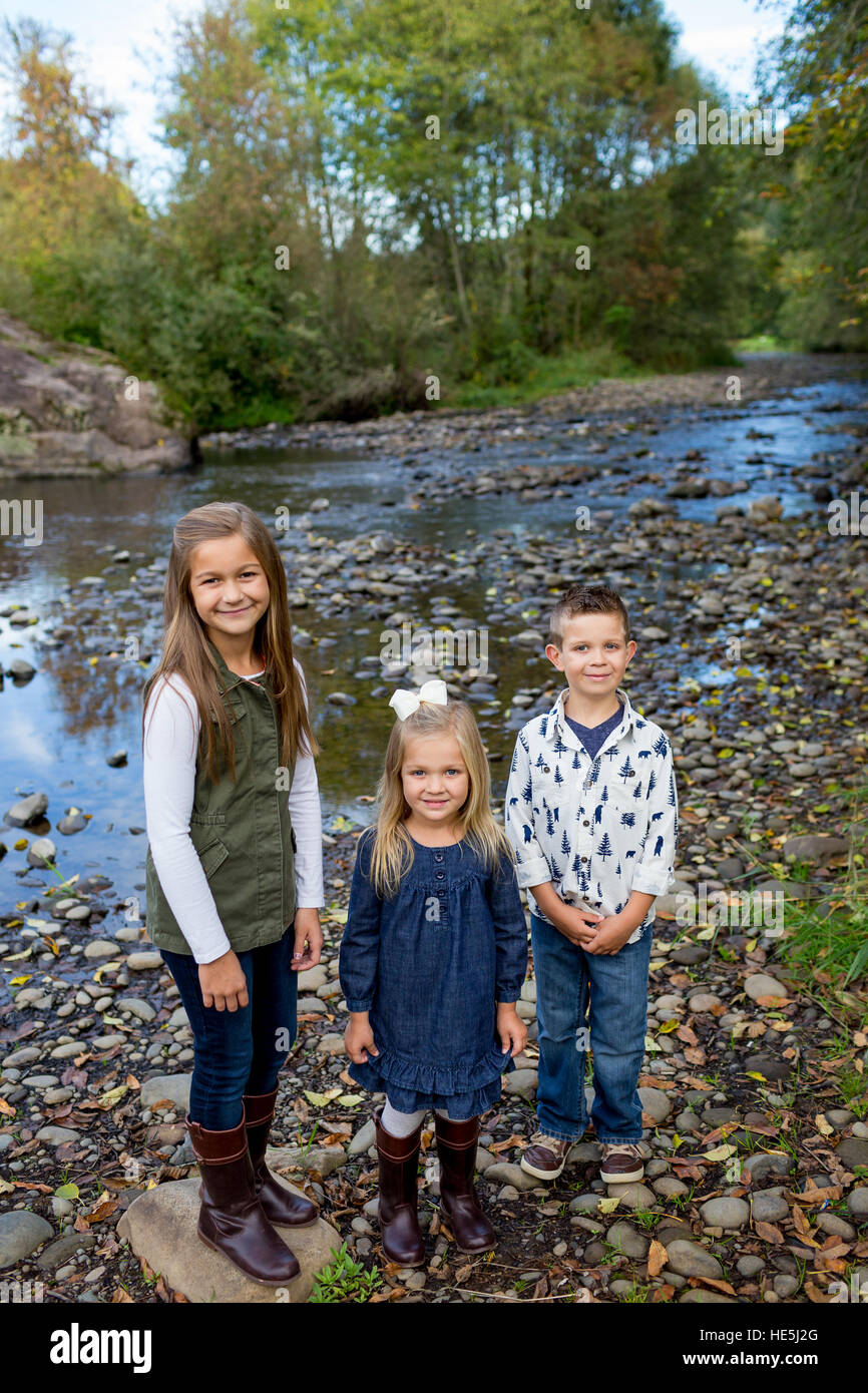 Three kids who are siblings in a candid lifestyle photo outdoors along the banks of the McKenzie River in Oregon. Stock Photo