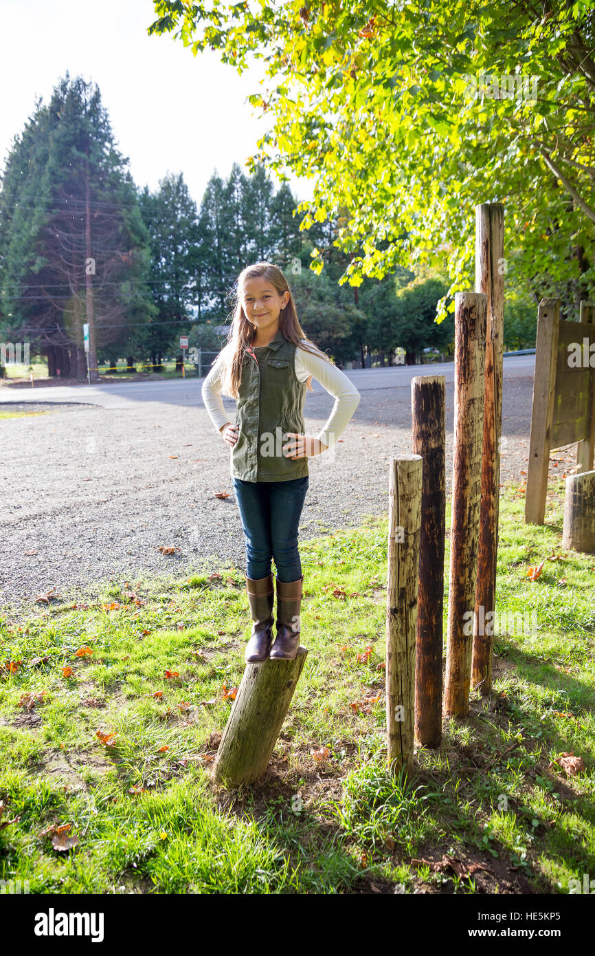Girl standing on a post having fun at a park. Stock Photo