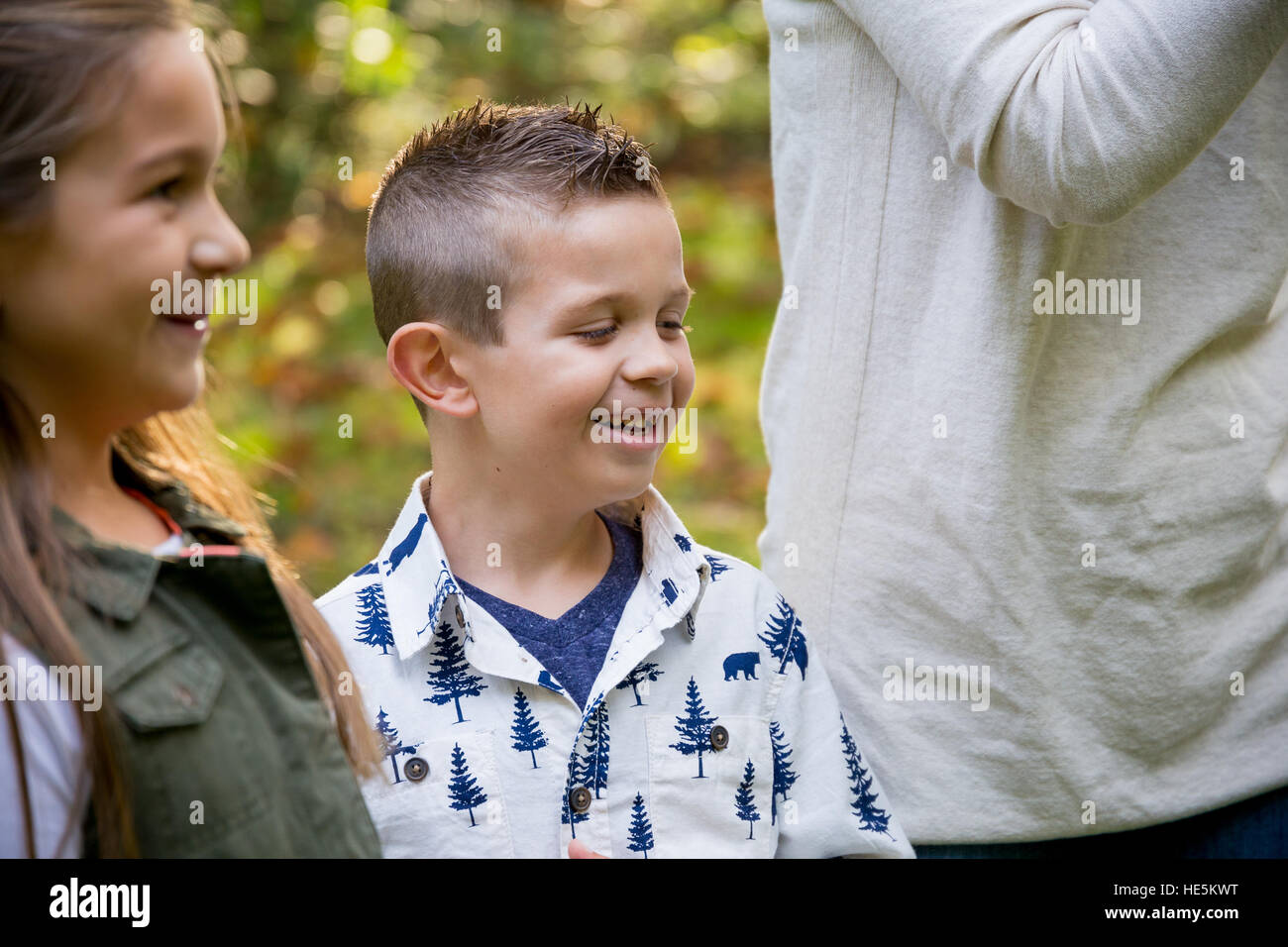 Candid lifestyle portrait of a young boy and his sister laughing and smiling at a nature park. Stock Photo