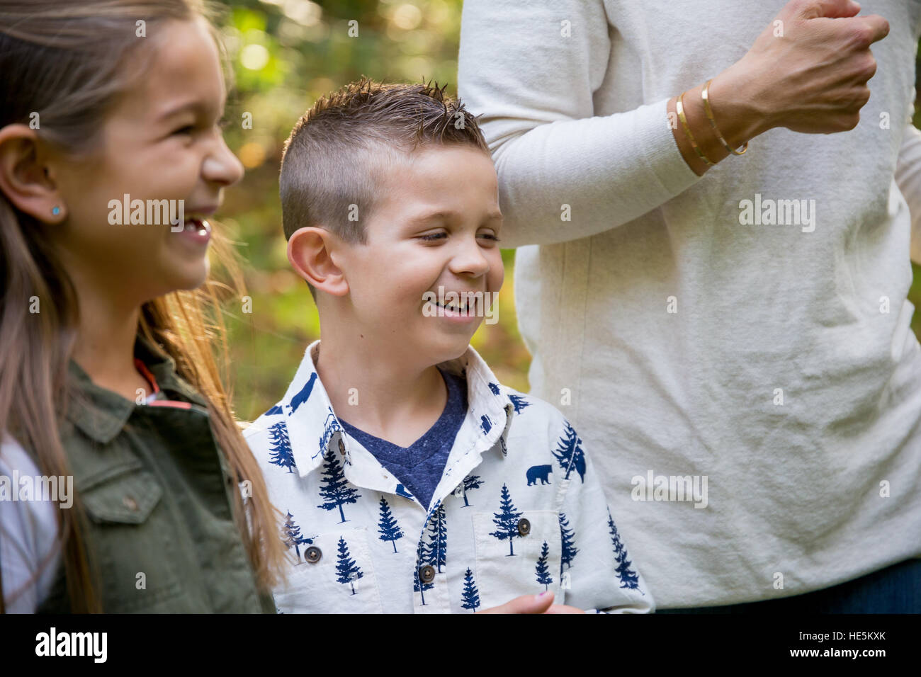 Candid lifestyle portrait of a young boy and his sister laughing and smiling at a nature park. Stock Photo