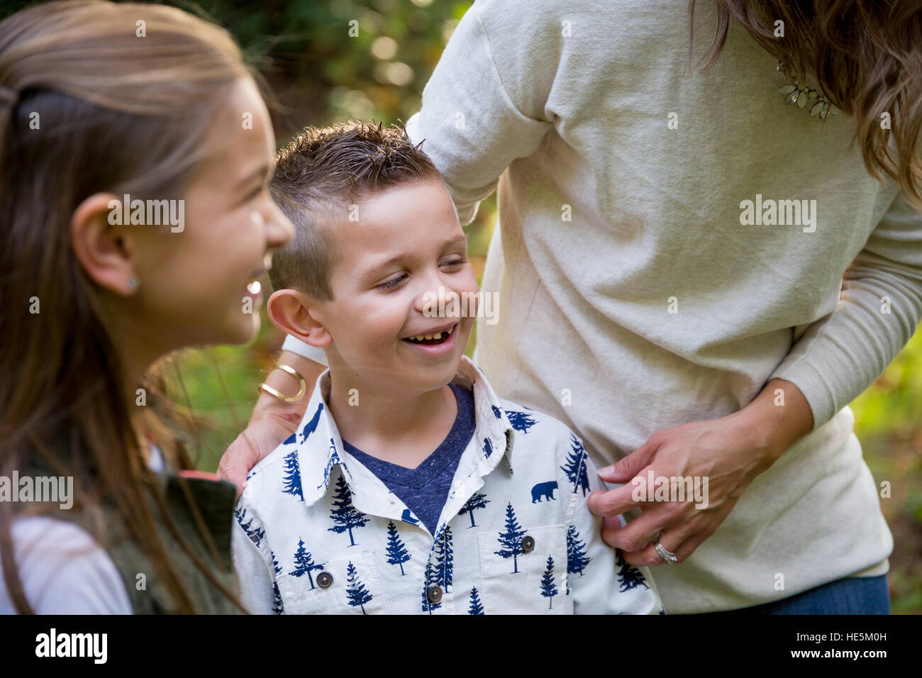 Candid lifestyle portrait of a young boy and his sister laughing and smiling at a nature park. Stock Photo