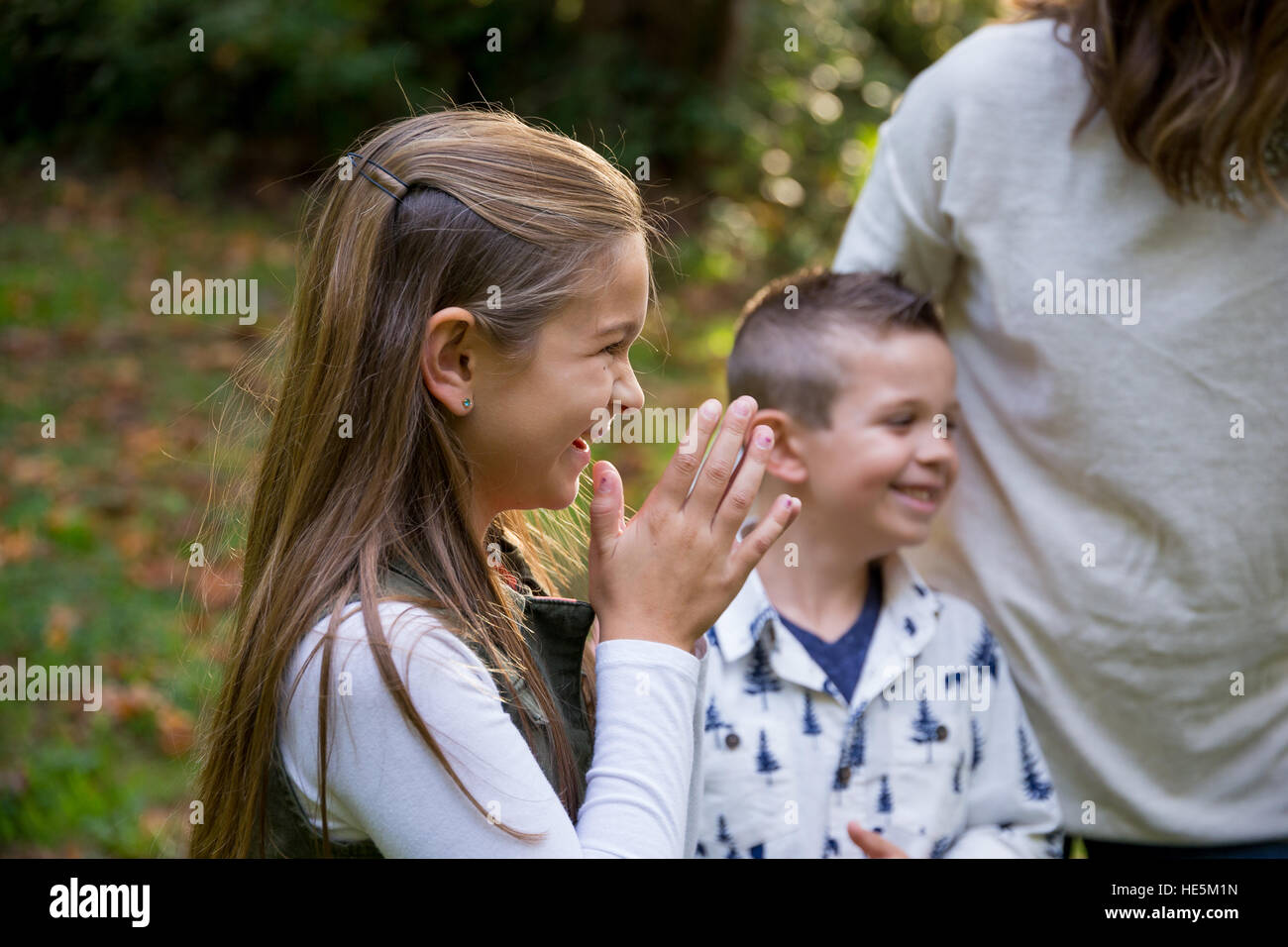 Candid lifestyle portrait of a young boy and his sister laughing and smiling at a nature park. Stock Photo