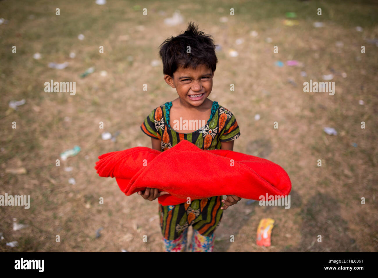 DHAKA, BANGLADESH - DECEMBER 17 : A street child shows her smile face after receive blanket in Dhaka, Banhladesh on December 17, 2016. About 44% people of Dhaka are homeless and they are living below of living condition. During winter many organization distribute warm cloths and blanket but these are not enough and sometime they made quarrel for them. Stock Photo